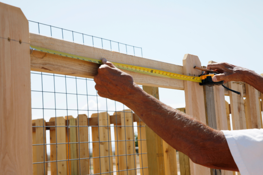 Professional contractor measuring and installing a custom wooden and wire fence, showcasing expert craftsmanship and quality fencing solutions by Alpine Fence in Kearny Mesa.